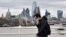 A pedestrian uses Waterloo Bridge to cross over the River Thames, backdropped by skyscrapers and offices of London on Jan. 29, 2022.