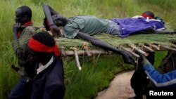 FILE - SPLA-IO (SPLA-in-Opposition) rebels carry an injured comrade after an assault on government SPLA (Sudan People's Liberation Army) soldiers, on the road between Kaya and Yondu, South Sudan, Aug. 26, 2017. 