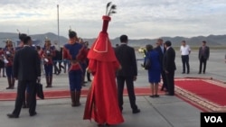 A Mongolian woman dressed in red traditional deel with LV shoes greets US Secretary of State John Kerry as her arrives in Ulaanbaatar, Mongolia. (N. Ching/VOA)