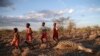 FILE — Maasai children run past a zebra that local residents said died due to drought, as they graze their cattle at Ilangeruani village, near Lake Magadi, in Kenya, on Nov. 9, 2022.