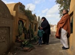 FILE - Lotfy Ibrahim's mother Tahany touches the face of a young relative during a visit to her son's grave with Lotfy's father, Khalil, near their home in Kafr al-Sheikh, Egypt, Jan. 13, 2019.
