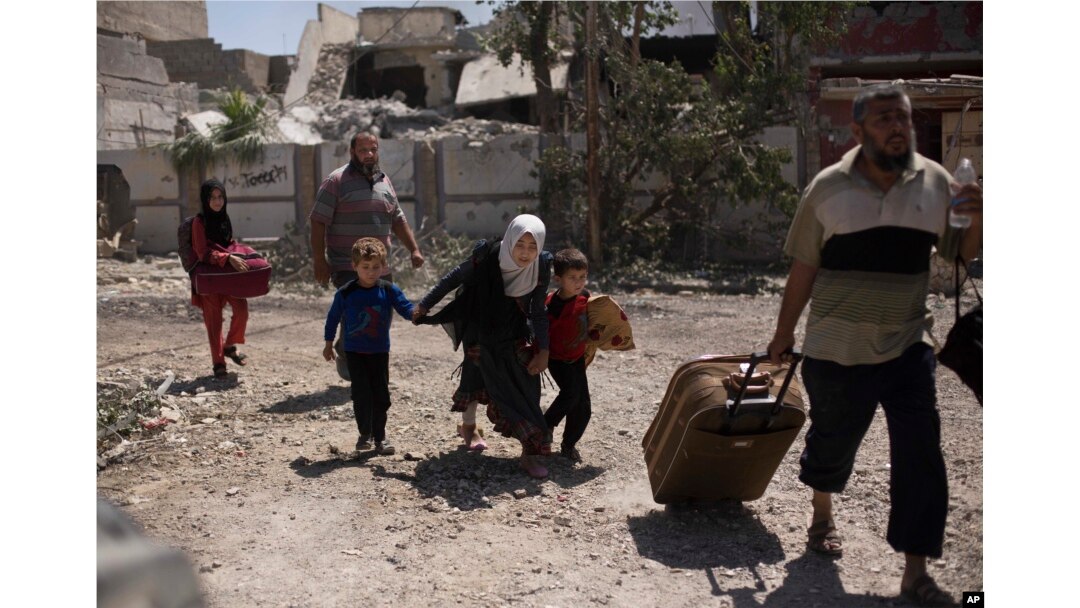 FILE - A girl ducks as she flees with her brothers in the al-Rifai neighborhood as Iraqi special forces battle Islamic State militants in western Mosul, Iraq, May 17, 2017.