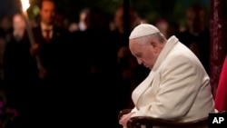 Pope Francis bows his heads and closes his eyes during the Via Crucis (Way of the Cross) torchlight procession in Rome, April 18, 2014. 
