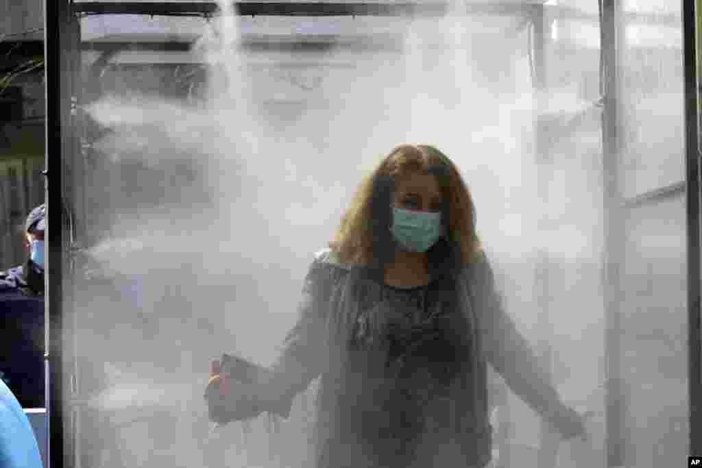 عبور یک زن از تونل مواد ضدعفونی کننده، قبل از ورود به مرکز خرید مواد غذایی در تیرانا، آلبانی