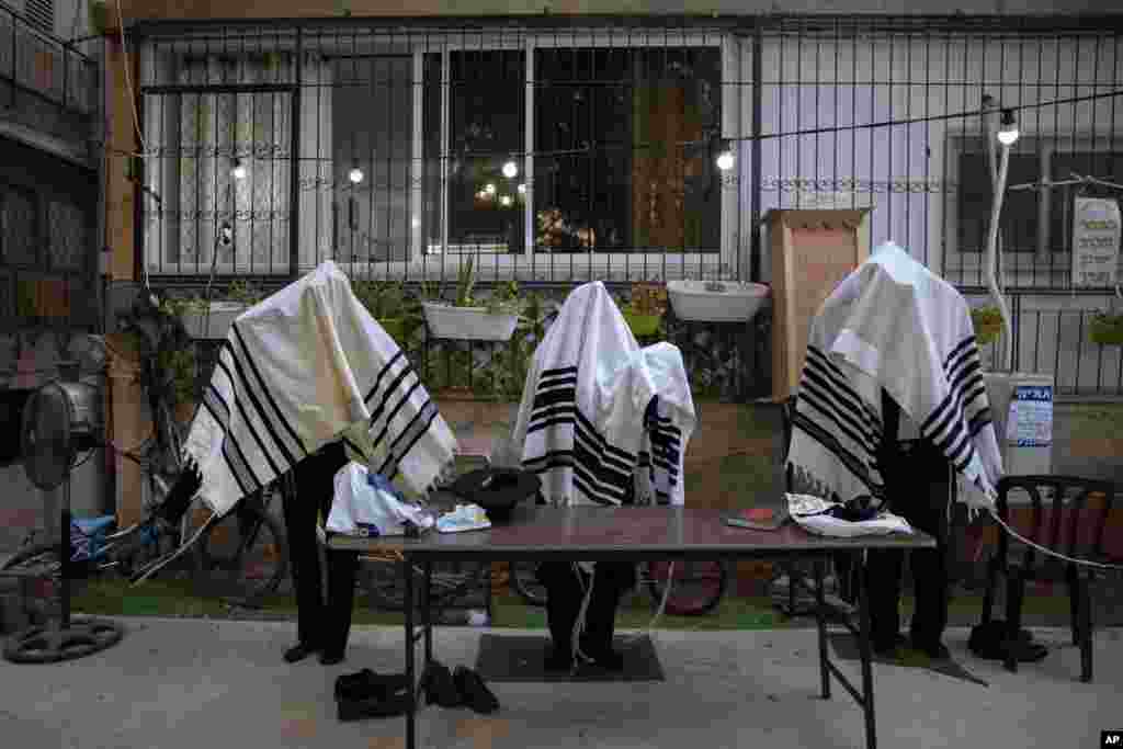 Ultra-Orthodox Jews covered in prayer clothing, pray in divided sections that permit a maximum of 20 worshipers because of the spread of the coronavirus, in Bnei Brak, Israel, Oct. 18, 2020.