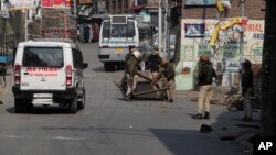 Polisi India memindahkan blokade yang dipasang oleh para demonstran di jalanan kota Srinagar, Kashmir-India menjelang kunjungan parlemen Uni Eropa hari Selasa (29/10). 