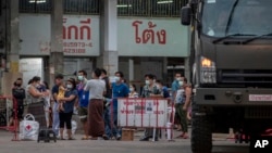 Migrant workers and their families are prepared to be taken to a field hospital for COVID-19 patents in Samut Sakhon, South of Bangkok, Thailand, Monday, Jan. 4, 2021. (AP Photo/Gemunu Amarasinghe)