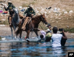 资料照片:美国边境巡逻人员骑马阻止海地移民从格兰德河的墨西哥一侧淌水进入美国边境城市德尔里奥。（2021年9月19日）