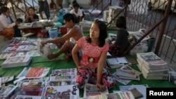 FILE - A woman sells newspapers in Yangon, Nov. 9, 2015. Access to newspapers is limited, as more and more media outlets have suspended operations after the February 1, 2021, military coup.