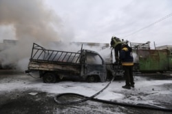 FILE -Firefighters hose down a truck after a government airstrike in the city of Idlib, Syria, Feb. 11, 2020. The latest violence in Idlib came as government forces came closer to capturing the last rebel-held part of a strategic highway, the M5.
