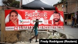 Un jeune homme passe devant une bannière de la candidate de l'opposition Xiomara Castro, à Tegucigalpa, au Honduras, le 27 novembre 2021.