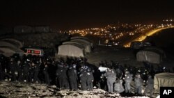 Polisi perbatasan Israel terlihat tengah mengusir aktivis Palestina dari tenda-tenda yang mereka dirikan di lokasi yang dikenal sebagai E1, dekat Yerusalem, 13 Januari 2013. (REUTERS/Ammar Awad). Petugas keamanan Israel dikabarkan telah mengevakuasi sekitar 100 orang Palestina, Minggu pagi dari wilayah tersebut.