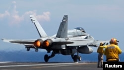 A U.S. Navy F/A-18 Hornet aircraft takes off during a tour of the USS Nimitz aircraft carrier on patrol in the South China Sea, May 23, 2013. 