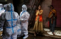 FILE - Health workers screen residents for COVID-19 symptoms at Dharavi, one of Asia's largest slums, in Mumbai, India, Aug. 3, 2020.