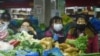 中国浙江省杭州市的一家超市里顾客戴着口罩购买蔬菜。（2020年2月9日）