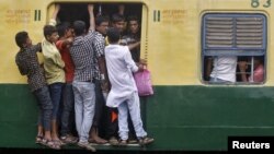 FILE - Commuters stand at an open doorway of a suburban train during the morning rush hour in Kolkata, India, July 31, 2015. India is set to overtake China and become the world's most populous country in less than a decade - six years sooner than previously forecast, the United Nations said in 2015.