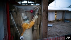 Seorang tenaga kesehatan mengenakan alat pelindung diri memasuki unit isolasi untuk merawat seorang pasien Ebola di pusat perawat Ebola di Beni, Republik Demokratik Kongo, 13 Juli 2019.