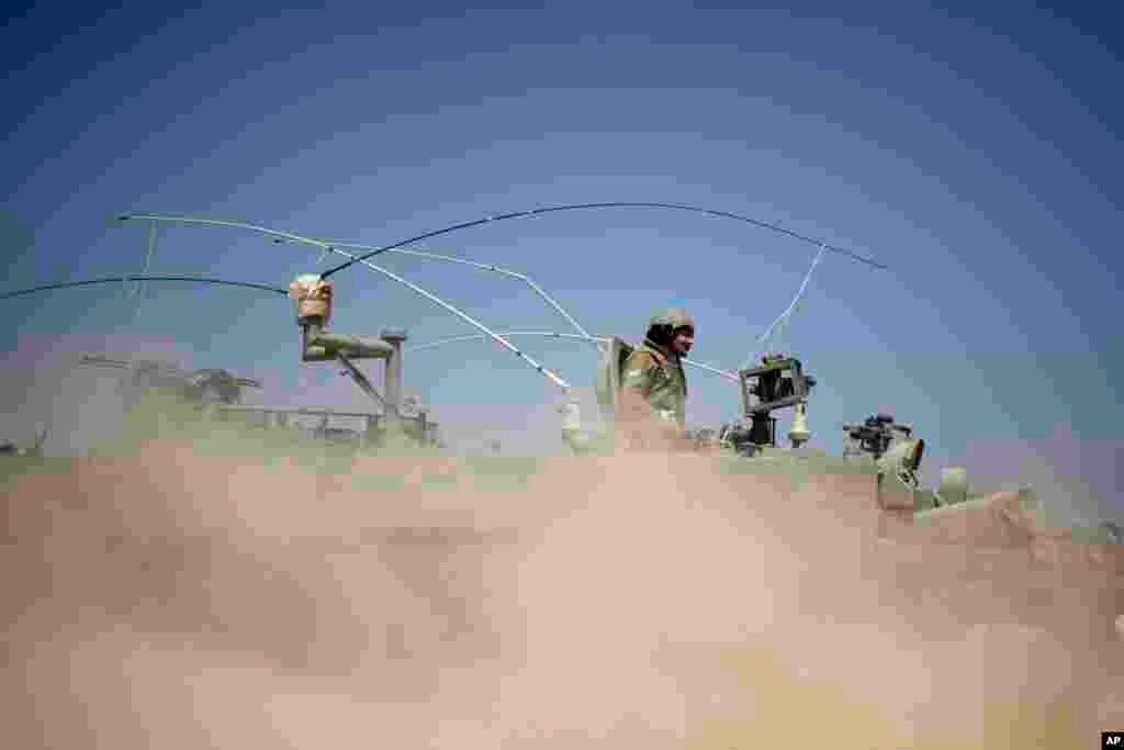 Israeli soldiers drive on an armored personal carrier near the Israel and Gaza Strip border, July 7, 2014. 