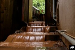 Water rushes down the stairs of a house near a mudslide that destroyed three homes on a hillside in Sausalito, Calif., Feb. 14, 2019.