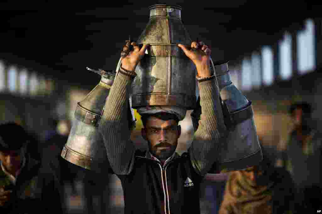 A milkman carries milk canisters early morning in Ghaziabad train station, on the outskirts of New Delhi, India.