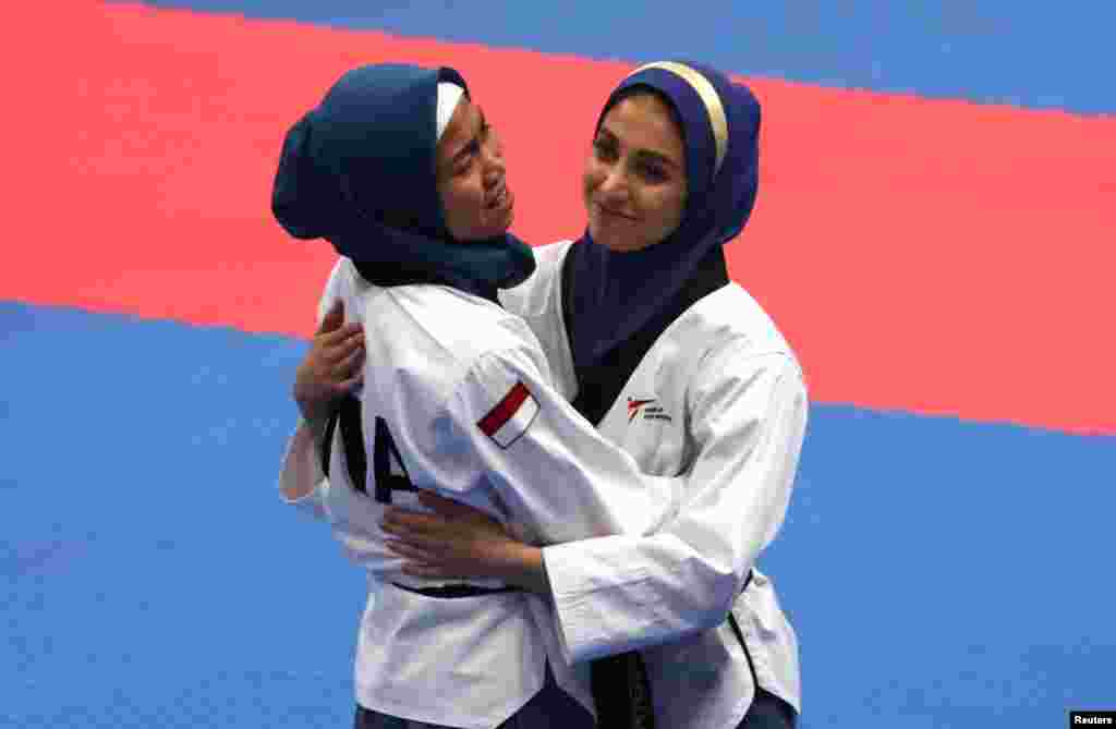 Atlet taekwondo Indonesia Defia Rosmaniar (kiri) yang meraih emas, mendapat ucapan selamat dari atlet Iran, Marjan Salahshouri yang meraih medali perak. (REUTERS/Cathal Mcnaughton)