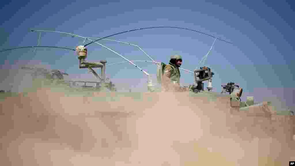 Israeli soldiers drive on an armored personal carrier near the Israel and Gaza Strip border, July 7, 2014. 