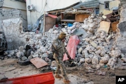 FILE - A soldier walks past rubble in the aftermath of an attack on the Afrik Hotel in Mogadishu, Somalia, Feb. 1, 2021. Al-Shabab claimed responsibility for the deadly assault.