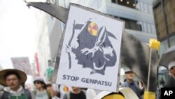 A boy wearing a mask holds a sign as he marches during an anti-nuclear protest in Tokyo, April 16, 2011.