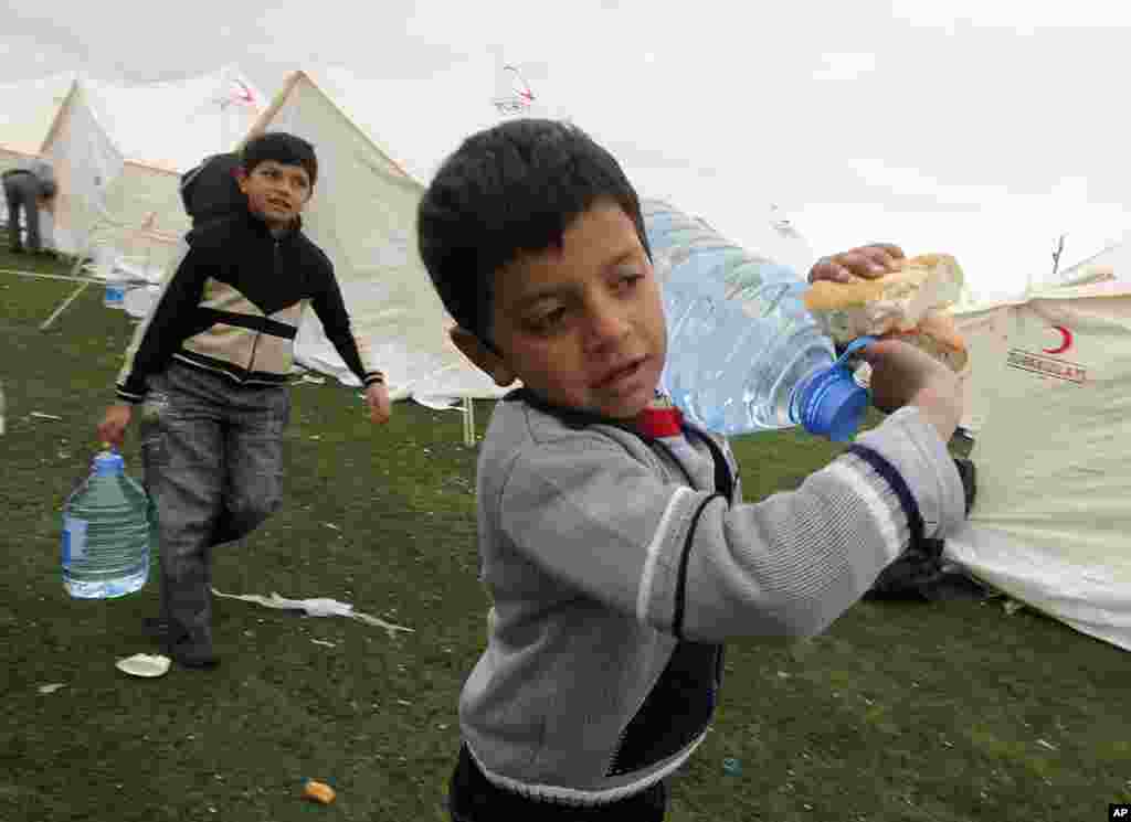 Earthquake survivors carry bottles of water back to their tent after receiving food aid in Ercis, near the eastern Turkish city of Van, October 27, 2011. (Reuters)
