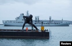 Patung perunggu terbesar Inggris, "Messenger" saat 'transit' di Plymouth Sound dengan tongkang, sebelum dibawa melalui jalan darat ke Theatre Royal di Plymouth, Inggris, 18 Maret 2019. (REUTERS / Peter Nicholls)
