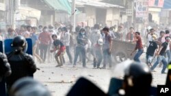 Garment workers throw objects at riot police during a strike near a factory of Canadia Center, on the Stung Meanchey complex at the outskirt of Phnom Penh, Cambodia, Friday, Jan. 3, 2014. Police wounded several striking Cambodian garment workers Friday when they opened fire to break up a labor protest, witnesses said.(AP Photo/Heng Sinith)