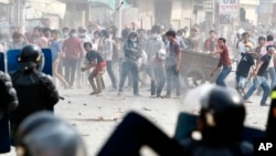 Garment workers throw objects at riot police during a strike near a factory of Canadia Center, on the Stung Meanchey complex at the outskirt of Phnom Penh, Cambodia, Friday, Jan. 3, 2014. Police wounded several striking Cambodian garment workers Friday when they opened fire to break up a labor protest, witnesses said.(AP Photo/Heng Sinith)Cambodia Labor Unrest
