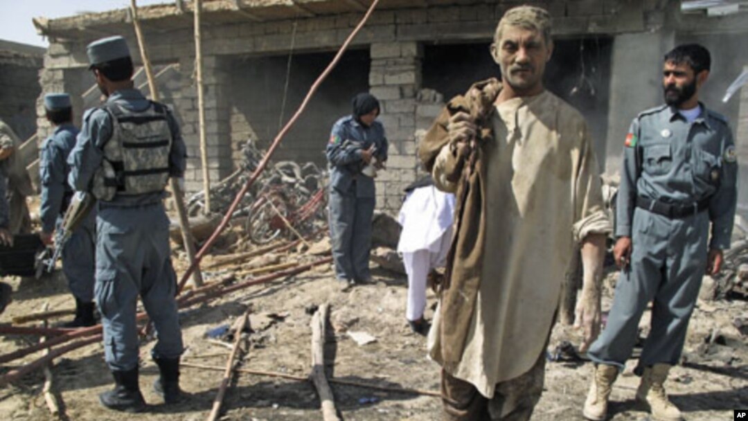 Police officers inspect the site of a suicide car bomb attack as a survivor leaves the scene, in Helmand province, Afghanistan, September 27, 2011.