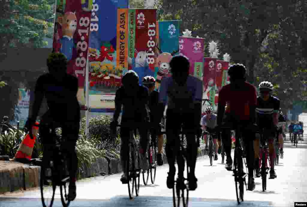 Para pengendara sepeda melintas di depan spanduk-spanduk promosi Asian Games saat hari bebas kendaraan di Jakarta, 15 Juli 2018. (Foto: Reuters)