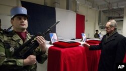 French Defense Minister Gerard Longuet (R) stands in front of the four coffins of French soldiers to pays his respects during a ceremony at Kabul Airport in Kabul on January 21, 2012.