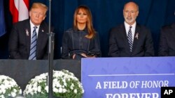 President Donald Trump, left and first lady Melania Trump, center, and Pennsylvania Governor Tom Wolf, listen as the names of the 44 people who died in the crash of Flight 93 are read during the September 11th Flight 93 Memorial Service in Shanksville, Pa