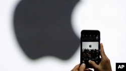 FILE - A person takes a photo of an Apple logo before an announcement of new products at the Apple Worldwide Developers Conference in San Jose, California, June 5, 2017.