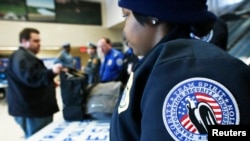 FILE - Members of the Transportation Security Administration (TSA) check a passenger's bags with N.J. Transit Police to secure mass transit for the Super Bowl XLVIII, in Secaucus, New Jersey, January 31, 2014. 