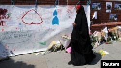 A woman walks past messages attached to a wall near the scene of an attack next to Finsbury Park Mosque, in north London, June 20, 2017. 