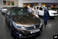 FILE - In this July 16, 2015 photo, Iranians look at a Renault sedan at a dealership in northern Tehran, Iran.