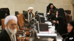 An Iranian cleric speaks with election staff while registering his candidacy for the February 26 Experts Assembly elections at the Interior Ministry in Tehran, Iran, Dec. 17, 2015.