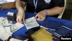 Un oficial de inmigración costarricense coloca una extensión de visa por 15 días más en un pasaporte cubano en Liberia, Costa Rica, el 26 de noviembre de 2015.