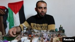 Palestinian artist Majdi Abu Taqeya works on small figures he carves from remains of Israeli ammunition collected from the scenes of border protests along the Israel-Gaza border, in the central Gaza Strip March 11, 2019. REUTERS/Ibraheem Abu Mustafa