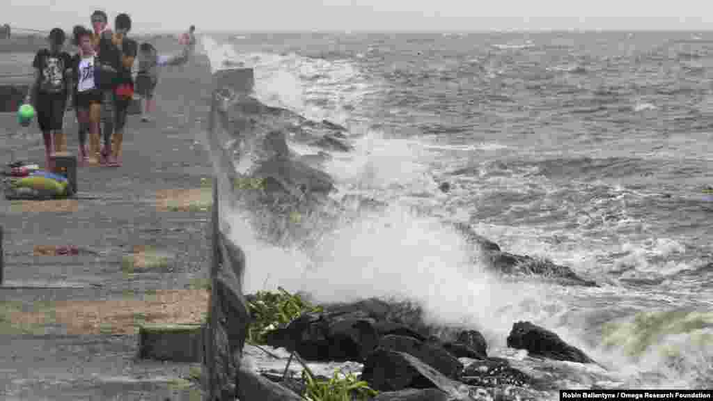 Youth walk on breakwater where rough waves caused by Typhoon Kalmaegi, also called Luis, are crashing, at Manila Bay, Philippines, Sept. 14, 2014. 