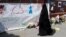 A woman walks past messages attached to a wall near the scene of an attack next to Finsbury Park Mosque, in north London, June 20, 2017. 
