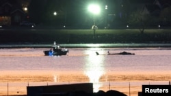 FILE - Rescuers approach wreckage of a Black Hawk helicopter that crashed into the Potomac River after it collided with an American Airlines jet approaching Reagan National Airport in Washington on Jan. 30, 2025. The NTSB is advising a ban on some helicopter flights in the area.