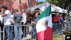 A fan holds a Mexican flag while he waits in line outside of the Miami-Dade County Auditorium during a public funeral for the late Mexican singer Jose Jose, Oct. 6, 2019, in Miami. 