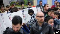 A worker, center, adjusts a ballot-filling booth as voters wait in lines at a polling station in the Brooklyn borough of New York, Nov. 8, 2016.