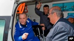 In this photo released by the Syrian official news agency SANA, Syrian prisoners Zeidan Tawil, left, and Khamis al-Ahmad, giving a victory sign, arrive to the Syrian side of the Quneitra crossing between Syria and the Israeli-occupied Golan Heights, April 28, 2019.
