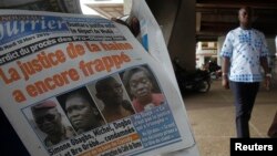 Un vendeur des journaux tient un numéro du Nouveau Courrier avec en manchette l'ancienne première dame Simone Gbagbo (2e à gauche, sur le journal), à Abidjan, le 10 mars 2015.